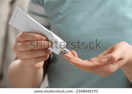 Woman applying ointment from tube onto her finger, closeup