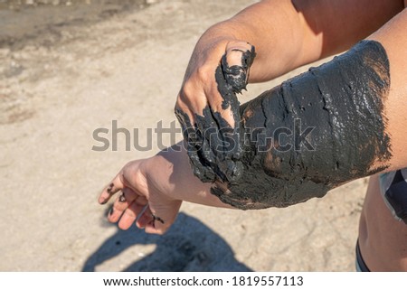 Woman applying on her body salty healing mud in Pomorie lake,Bulgaria