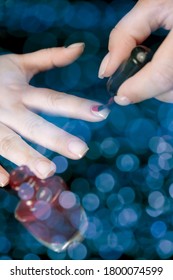 Woman applying red nail polish on her fingernails
