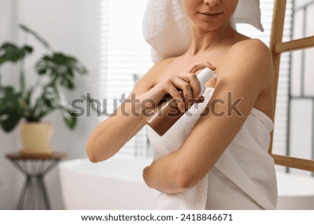 Woman applying self-tanning product onto arm in bathroom, closeup. Space for text