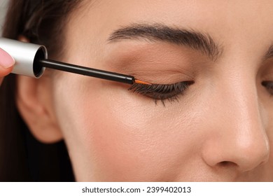 Woman applying serum onto her eyelashes, closeup. Cosmetic product