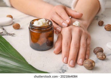 Woman applying shea butter onto hands on light background - Shutterstock ID 2021864084