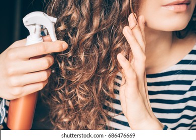 Woman Applying Spray On Curly Brown Hair Close-up