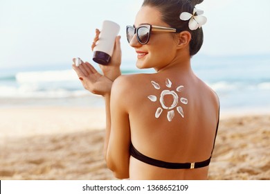 Woman Applying Sun Cream  on Tanned  Shoulder In Form Of The Sun. Sun Protection.Sun Cream. Skin and Body Care. Girl Using Sunscreen to Skin. Female Holding Suntan Lotion and Moisturizing Sunblock.