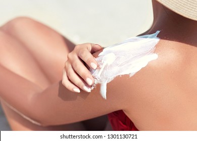 Woman Applying Sun Protection On Tanned Back. Skincare. Body Sun Protection Suncream. Bikini Hat Woman Applying Moisturizing Sunscreen Lotion On Back.