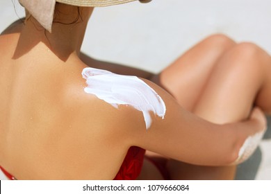 Woman Applying Sunscreen Creme On  Tanned  Shoulder. Skincare. Body Sun Protection Suncream. Bikini Hat Woman Applying Moisturizing Sunscreen Lotion On Back.