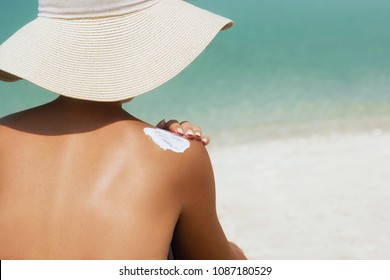 Woman Applying Sunscreen Creme On  Tanned  Shoulder. Skincare. Body Sun Protection Suncream. Bikini Hat Woman Applying Moisturizing Sunscreen Lotion On Back.