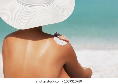 Woman Applying Sunscreen Creme On  Tanned  Shoulder. Skincare. Body Sun Protection Suncream. Bikini Hat Woman Applying Moisturizing Sunscreen Lotion On Back.