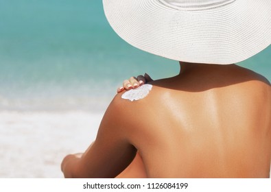 Woman Applying Sunscreen Creme On  Tanned  Shoulder. Skincare. Body Sun Protection Suncream. Bikini Hat Woman Applying Moisturizing Sunscreen Lotion On Back.