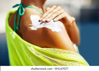 Woman applying sunscreen on her shoulder - Shutterstock ID 591147077