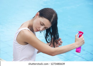 Woman applying sunscreen spray, hair care protection during summer vacation