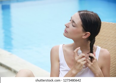 Woman applying sunscreen spray, hair care protection during summer vacation