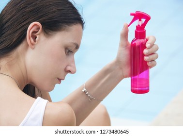Woman applying sunscreen spray, hair care protection during summer vacation