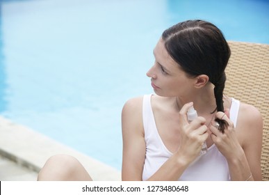 Woman applying sunscreen spray, hair care protection during summer vacation