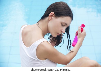 Woman applying sunscreen spray, hair care protection during summer vacation