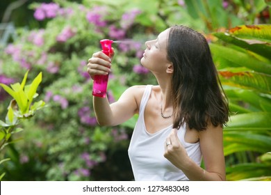 Woman applying sunscreen spray, hair care protection during summer vacation