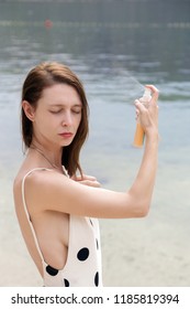 Woman applying sunscreen spray on the beach, hair care protection concept