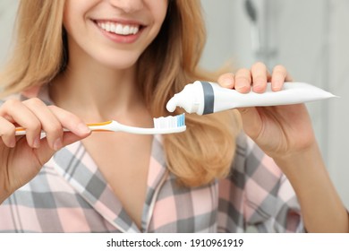 Woman Applying Toothpaste On Brush Indoors, Closeup