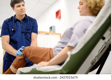 Woman at an appointment with rheumatologist talks about pain symptom of knee joint. Orthopedic doctor examines a patient. Rheumatology deals with circulatory, lymphatic systems and autoimmune diseases