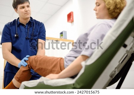 Woman at an appointment with rheumatologist talks about pain symptom of knee joint. Orthopedic doctor examines a patient. Rheumatology deals with circulatory, lymphatic systems and autoimmune diseases