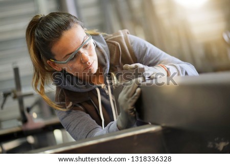 Woman apprentice training in metalwork workshop