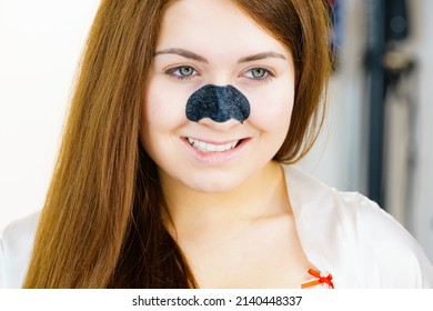 Woman appying clear-up strips on nose, using pore cleansing textile mask for blackheads. Girl taking care of skin complexion. Beauty treatment. Skincare.