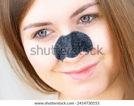 Woman appying clear-up strips on nose, using pore cleansing textile mask for blackheads. Girl taking care of skin complexion. Beauty treatment. Skincare.