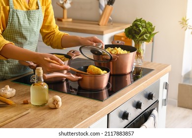 Woman in apron preparing corn cobs in kitchen - Powered by Shutterstock