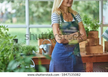 Woman in apron standing with crossed hands