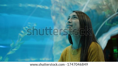 Woman in the aquarium, and look at the fish inside