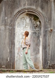 Woman in arch of ancient architecture outdoors. Arched stone stucco structure of ancient architecture. Tourist walk through abandoned places