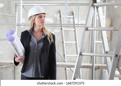 Woman Architect Or Construction Engineer Bring Under Arm Blueprint Wear Helmet Inside A Building Site Scaffolding In The Background