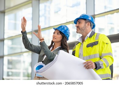 Woman architect explaining blueprint to supervisor at construction site. Mid adult contractor holding blueprint and understanding manager vision at construction site. Engineer talking to contractor. - Powered by Shutterstock