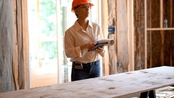 Woman Architect Reviewing Blueprints With Computer Tablet In A New Home Construction Project Inspection.