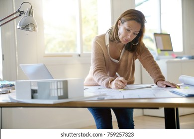 Woman Architect Working On Blueprints In Office