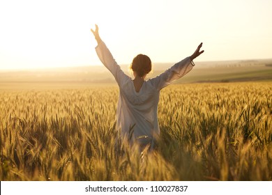 Woman with arms outstretched in a wheat field