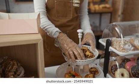 Woman arranging baked goods in a bakery shop with gloves and brown apron in an indoor setting, showcasing a variety of pastries and desserts. - Powered by Shutterstock