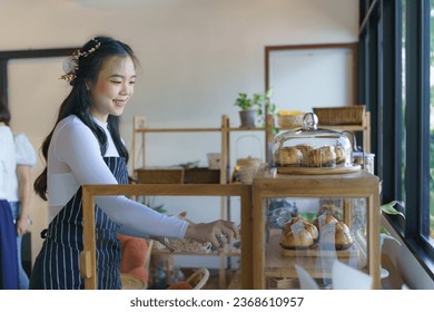 A woman, arranging bakery bread in a tray, is preparing for sale in a bakery. - Powered by Shutterstock