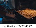 A woman arranging freshly cut potato slices on a baking tray to make oven-baked French fries. The photo highlights a simple and tasty way to enjoy homemade fries at home.