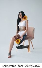 Woman With Artificial Leg Sitting At The Chair While Posing At The Studio With Sunflowers