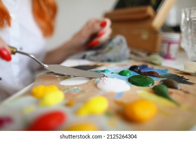 Woman Artist Evens Paint With A Spatula On A Wooden Palette. Hands With Manicure Pick Up Paint For Painting With A Spatula