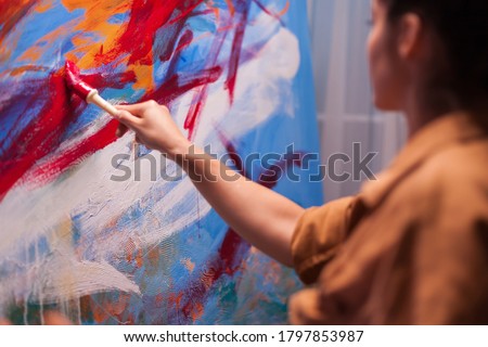 Woman artist holding paint brush on large canvas in art studio. Modern artwork paint on canvas, creative, contemporary and successful fine art artist drawing masterpiece