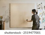 Woman artist painting on a big blank canvas, woman artist working in art studio with blank canvas, woman artist painting in art studio, woman artist with big blank canvas to paint in the room