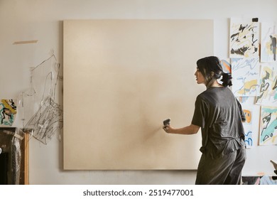 Woman artist painting on a big blank canvas, woman artist working in art studio with blank canvas, woman artist painting in art studio, woman artist with big blank canvas to paint in the room - Powered by Shutterstock