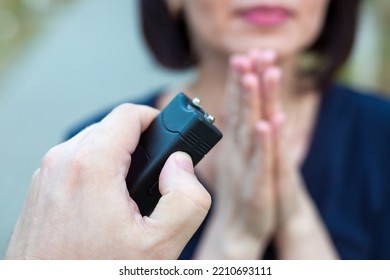 Woman Asking For Mercy In Front Of A Criminal With A Stun Gun.