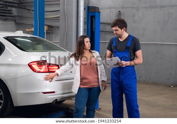 A woman asks a\
mechanic about a car repair