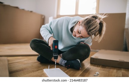 Woman assembling furniture at home with cordless screwdriver - Powered by Shutterstock