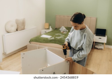 Woman assembling furniture at home with cordless screwdriver - Powered by Shutterstock