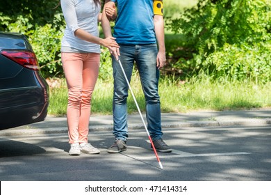 Woman Assisting Blind Man With White Stick On Street