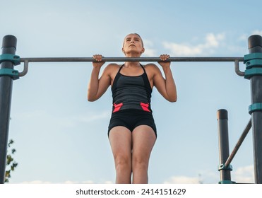 woman athlete doing pull ups on a bar outdoors. calisthenics - Powered by Shutterstock